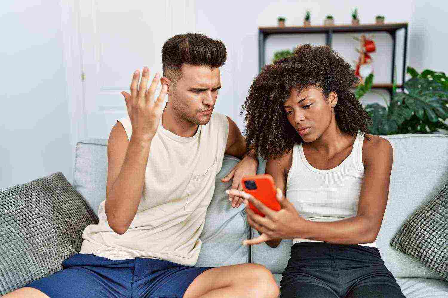 man woman couple with problems using smartphone home