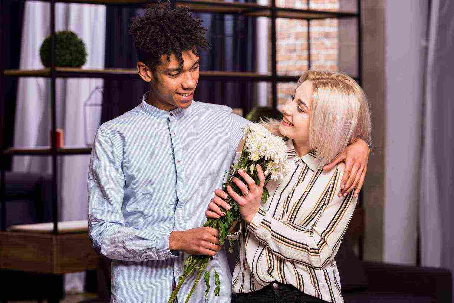 portrait smiling interracial young couple holding white flower bouquet