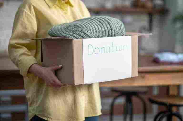 cropped photo female volunteer holding carton full clothes prepared donation