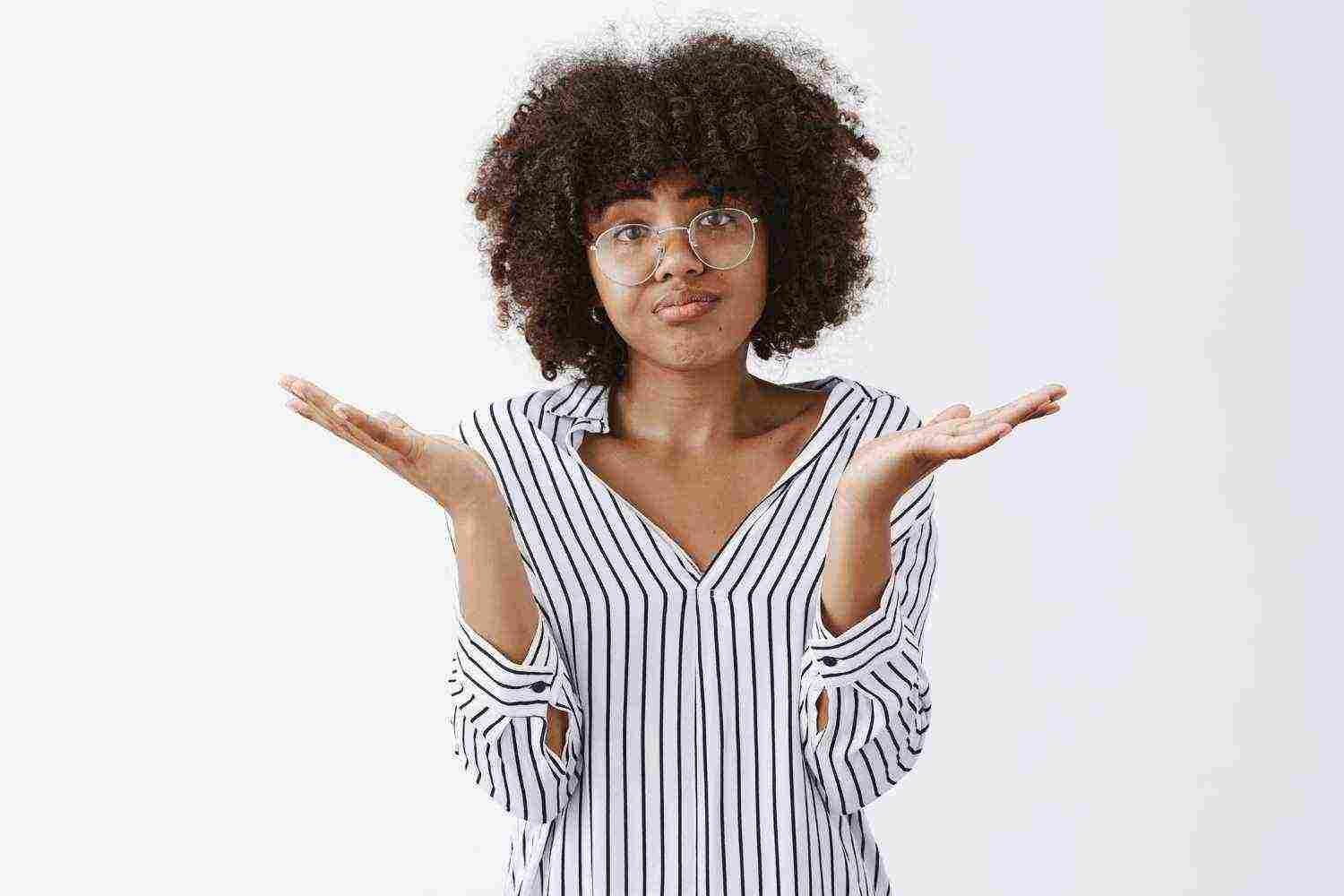 upset woman losing battle shrugging with spread palms aside pursing lips frowning from disappointment regret being unhappy gloomy after bad result gray wall