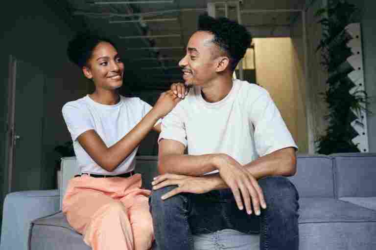 young attractive cheerful casual african american couple happily looking each other sofa modern home1