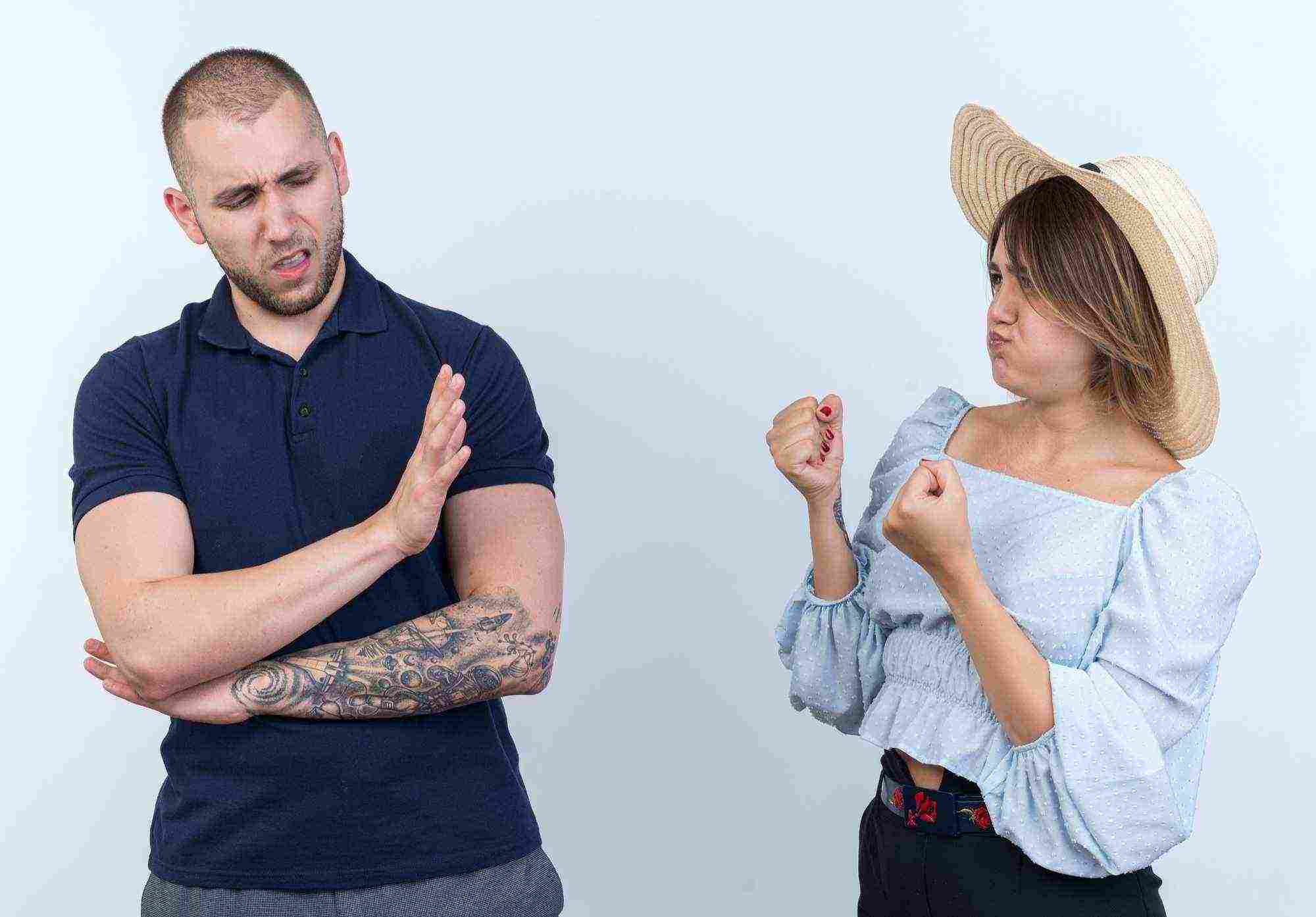 young beautiful couple man woman quarreling angry woman with clenched fists looking her boyfriend who makes stop gesture with hand standing