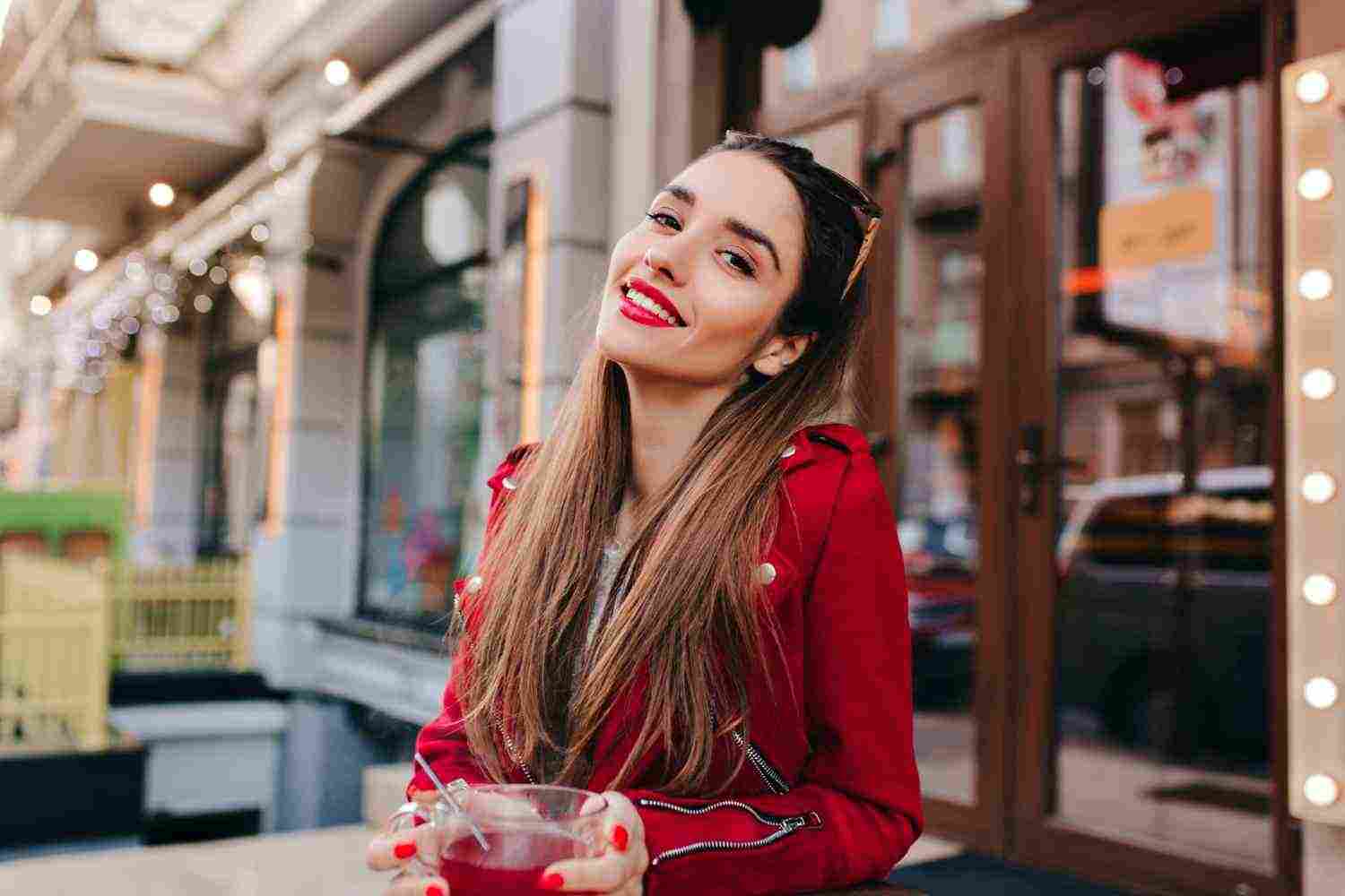 adorable woman with trendy makeup laughing while drinking tea street space