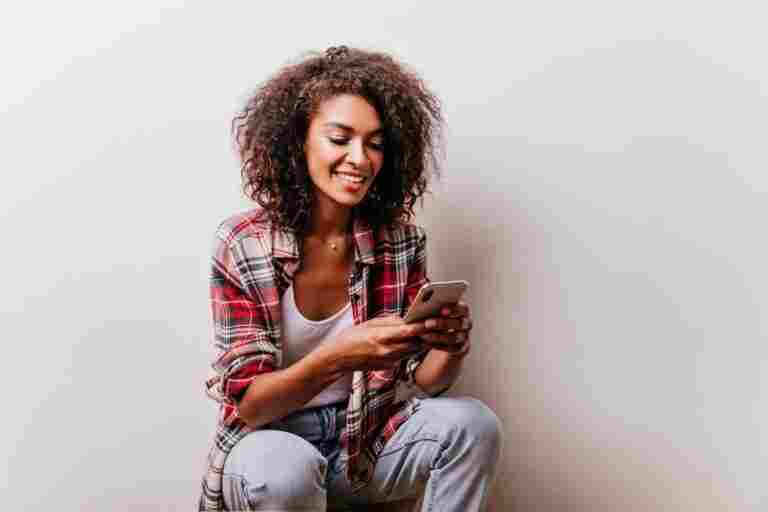 blithesome black woman checkered shirt using her smartphone appealing girl reading phone message