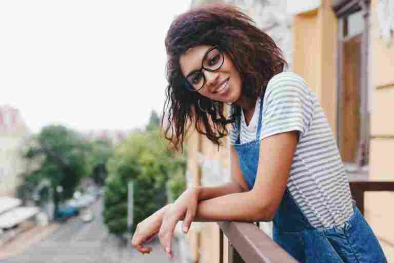 charming curly young woman glasses posing while standing terrace enjoying city views
