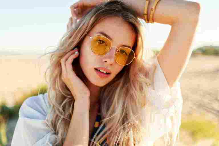 close up portrait playful smiling blonde girl playing with hairs having fun enjoying summer beach