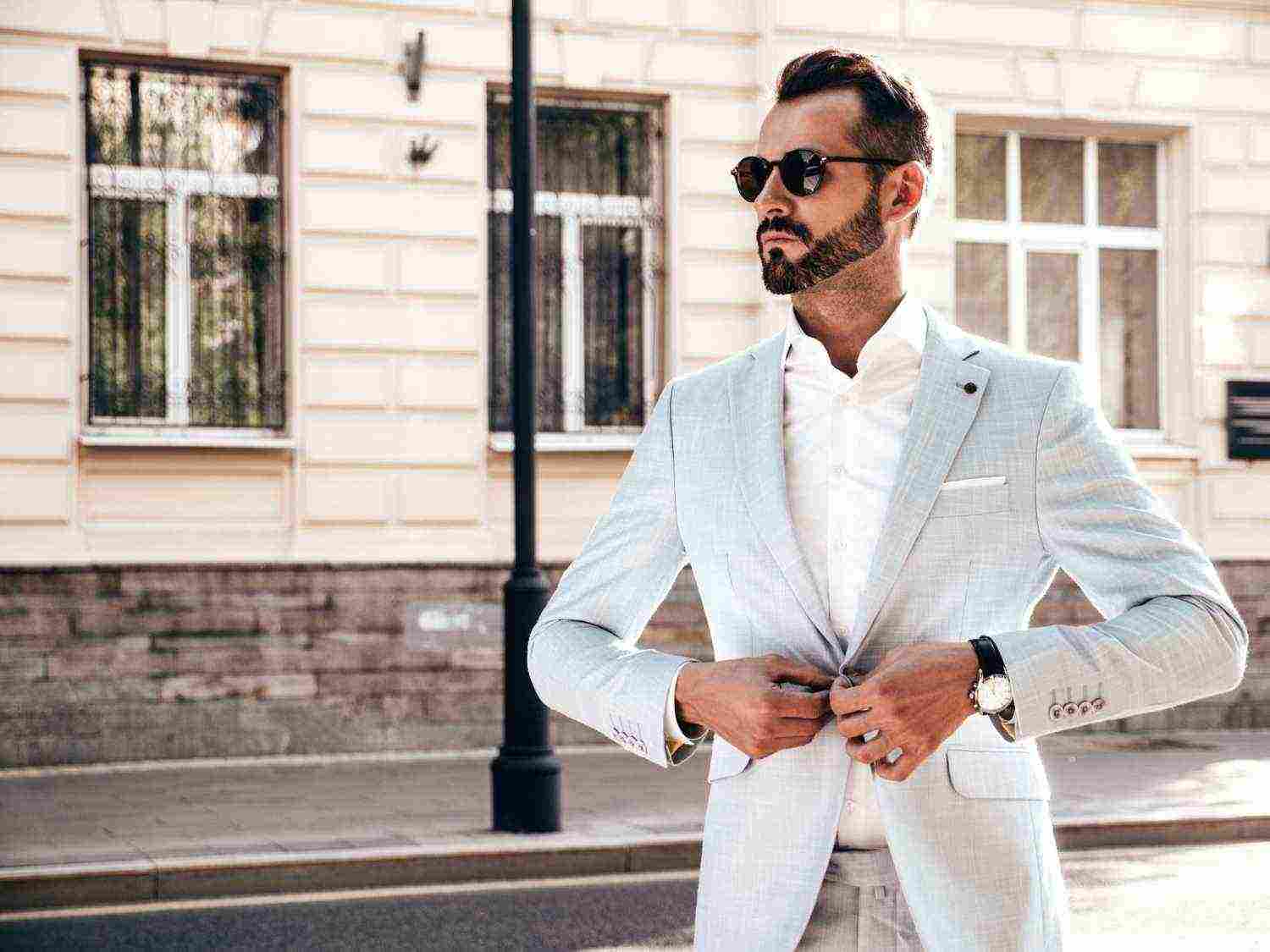 portrait handsome confident stylish hipster lambersexual modelmodern man dressed elegant white suit fashion male posing street background europe city sunset sunglasses