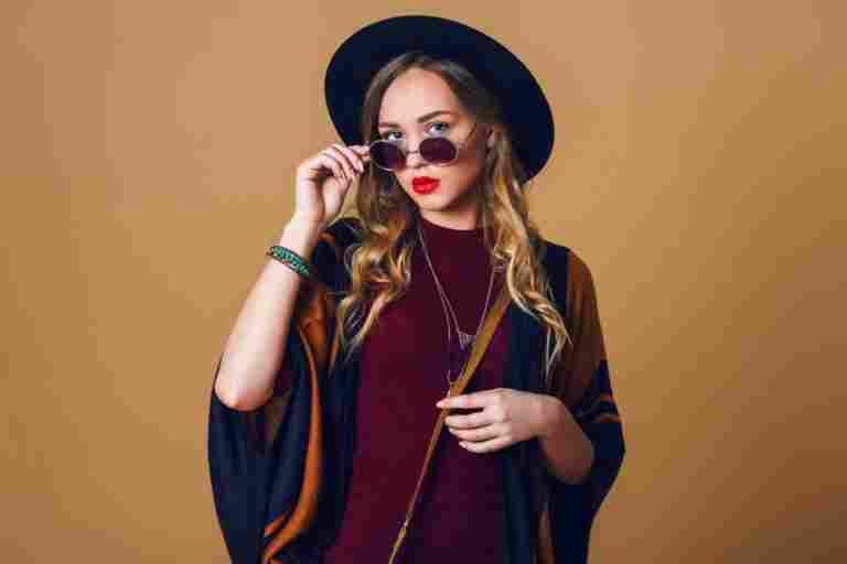 studio close up portrait young fresh blonde woman brown straw poncho wool black trendy hat round glasses looking camera green leather had bag