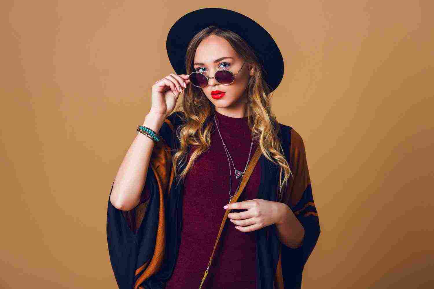 studio close up portrait young fresh blonde woman brown straw poncho wool black trendy hat round glasses looking camera green leather had bag