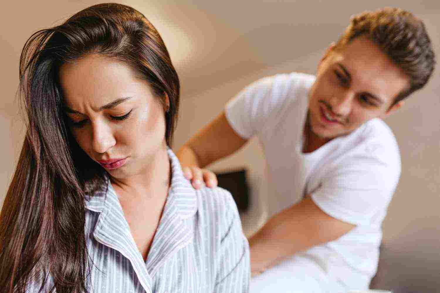 upset brunette woman pajama looking down while husband talk her