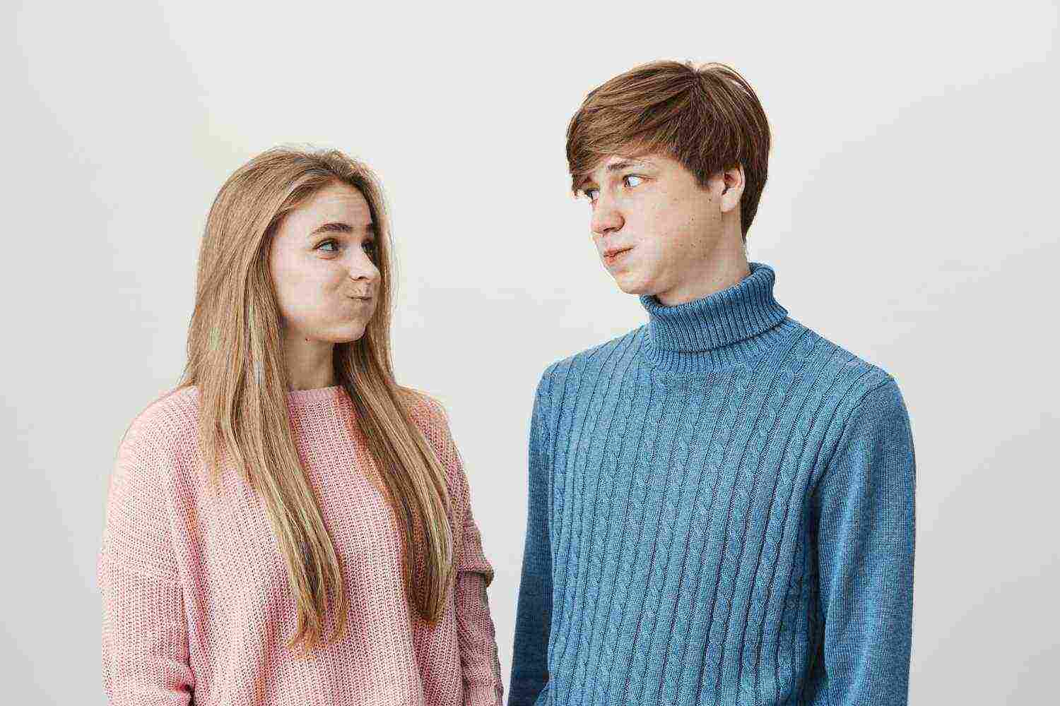 waist up portrait young female male wearing knitted colourful sweaters having discontent looks pouting cheeks