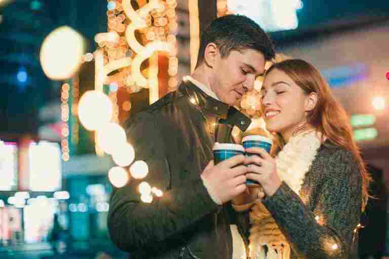 young couple kissing hugging outdoor night street christmas time