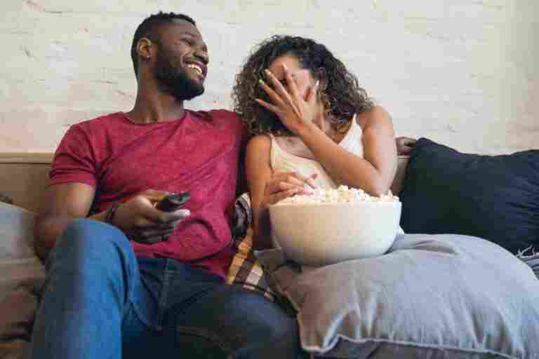 young couple watching horror movie while sitting couch home