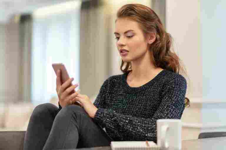 attractive young woman looking her smart phone home woman types message her smart phone