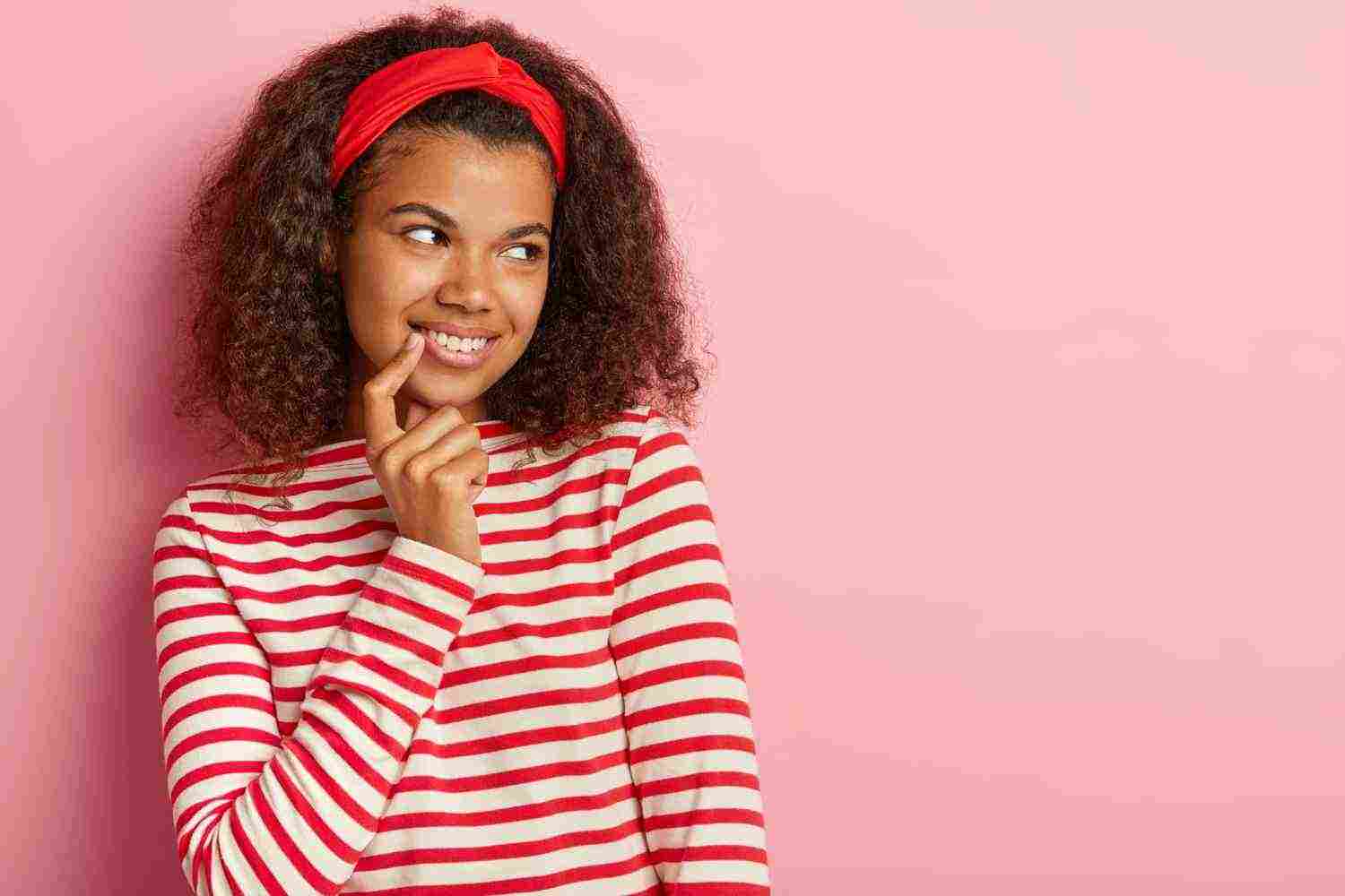 candid shot pensive teenage girl with curly hair posing striped red sweater