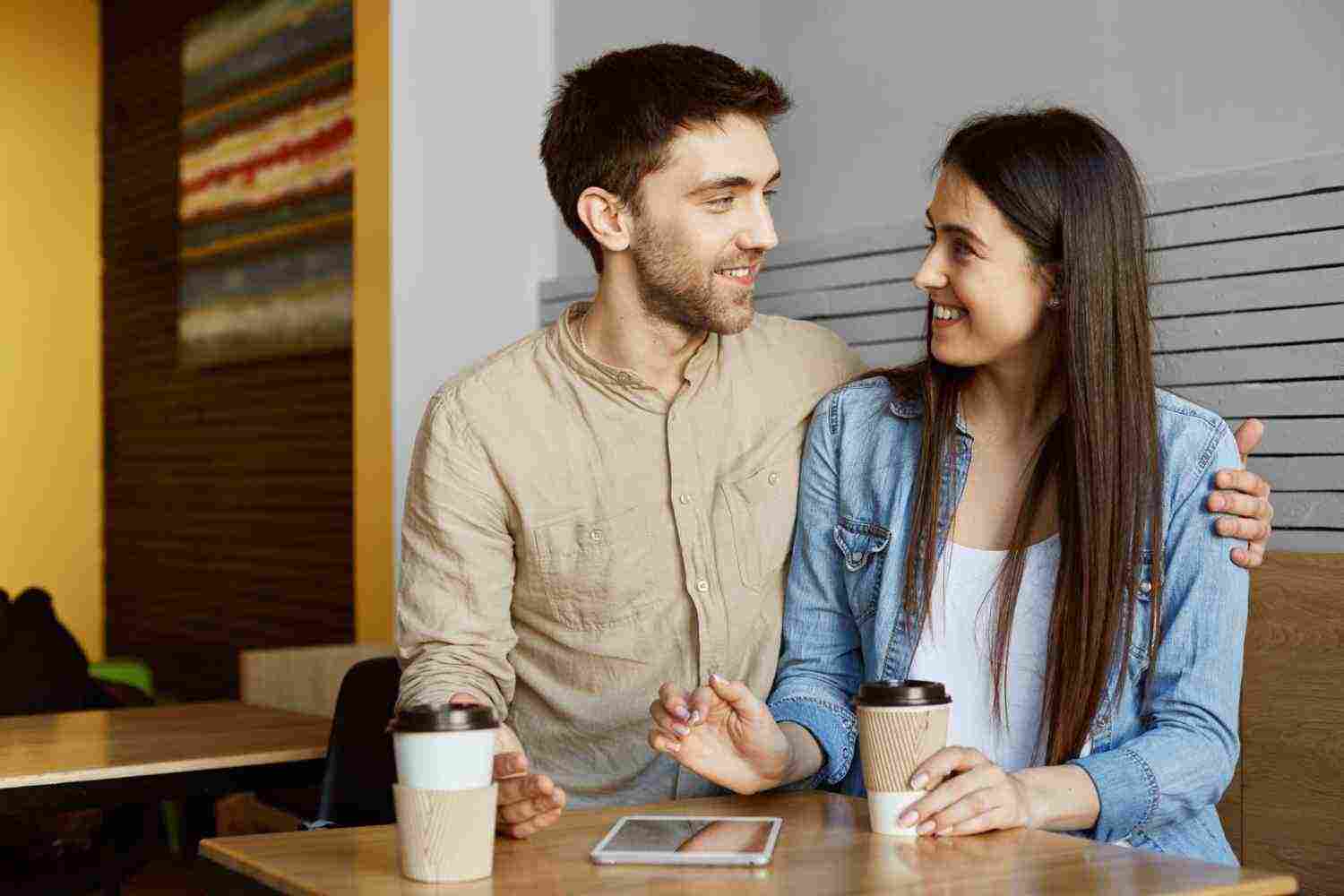 happy young couple two stylish students sitting cafeteria drinking coffee smiling hugging talking about their life