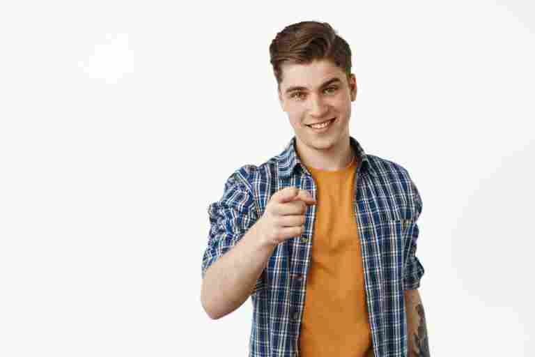 he choose you smiling young man student boy pointing finger camera recruiting people invite event join our company gesture stands against white background