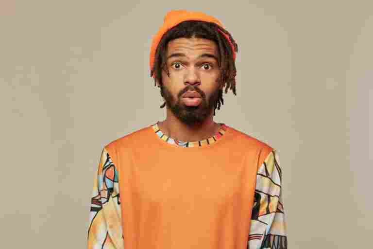 studio portrait young african american man posing studio background looking into camera with shocked facial expression