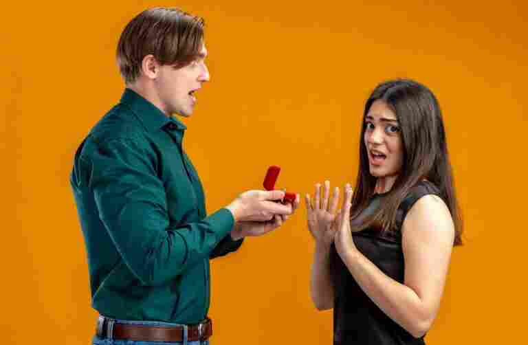 young couple valentines day angry guy giving wedding ring unpleased girl isolated orange background