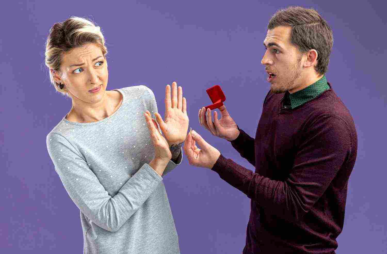 young couple valentines day confused guy giving wedding ring unpleased girl isolated blue background