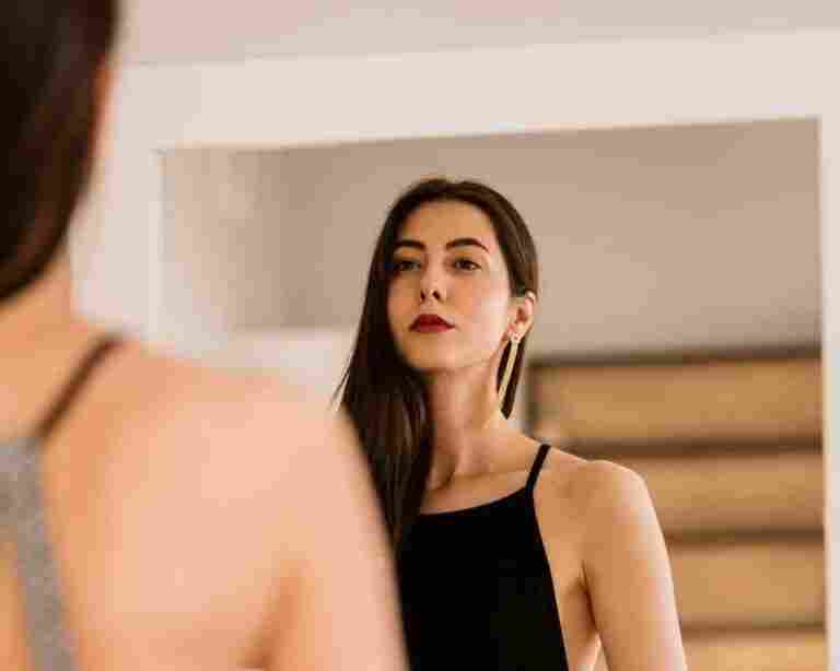 lady wears beautiful black dress looking into mirror