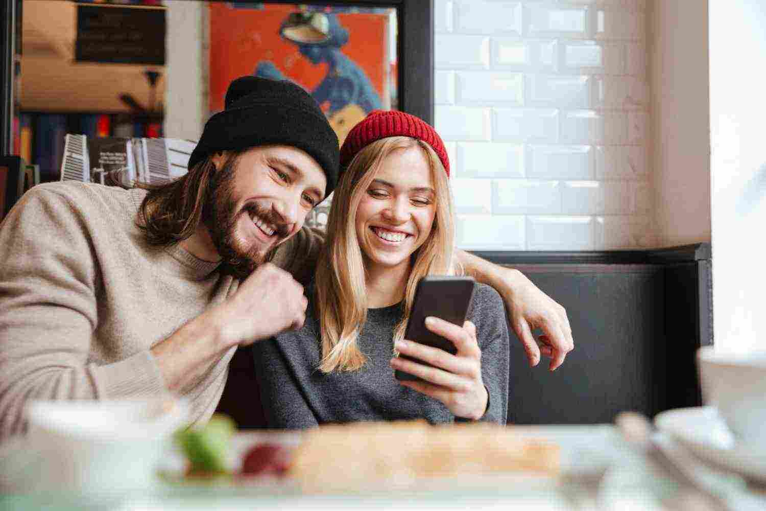 laughing couple looking phone cafe