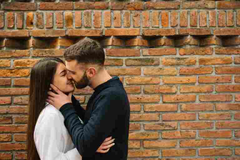 young couple kissing front wall