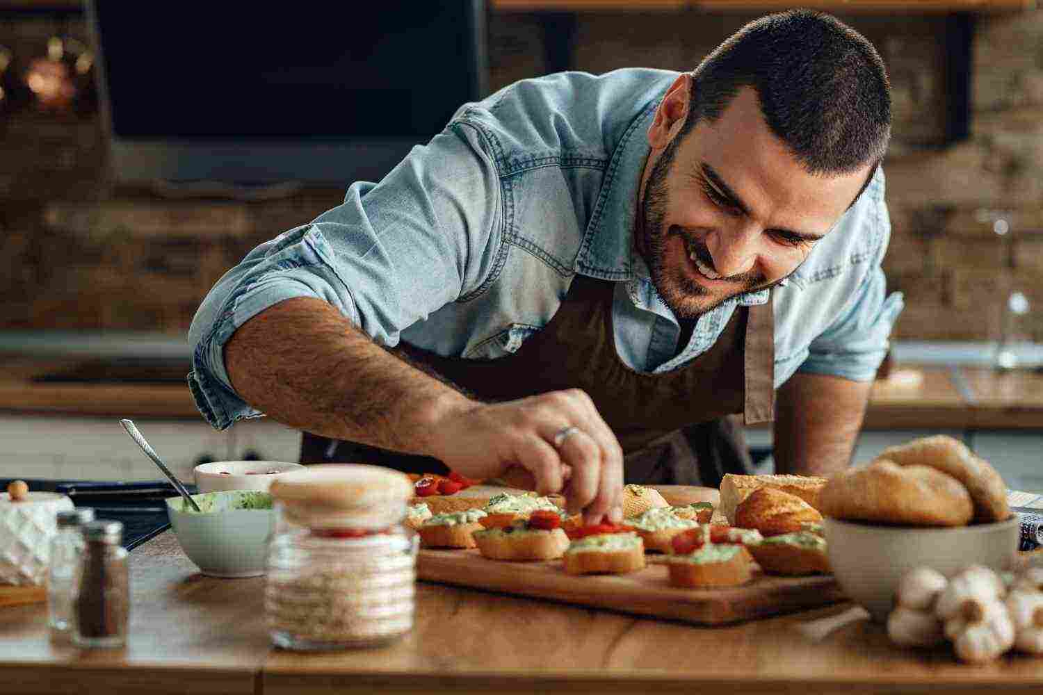 young happy cook preparing bruschetta with avocado sauce cherry tomato kitchen