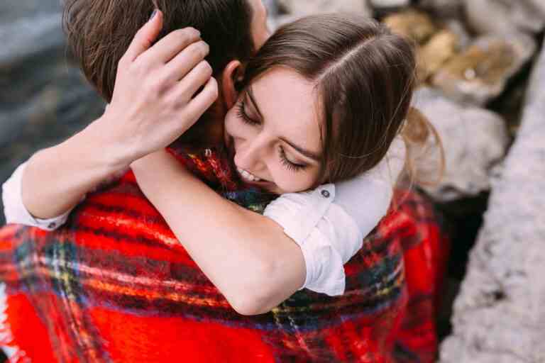 beautiful young couple sitting stone embankment wrapped blanket