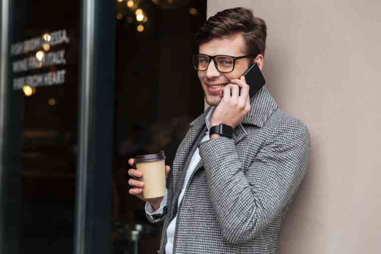 cheerful businessman eyeglasses coat talking by smartphone