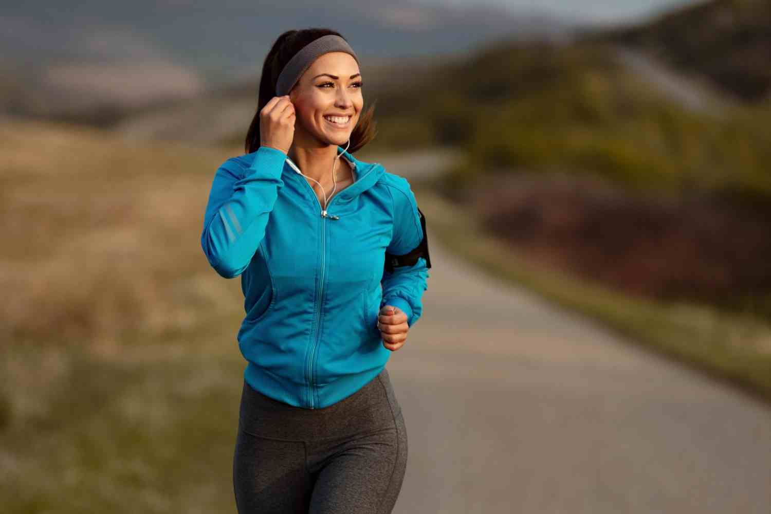 happy athletic woman listening music earphones while running nature morning copy space