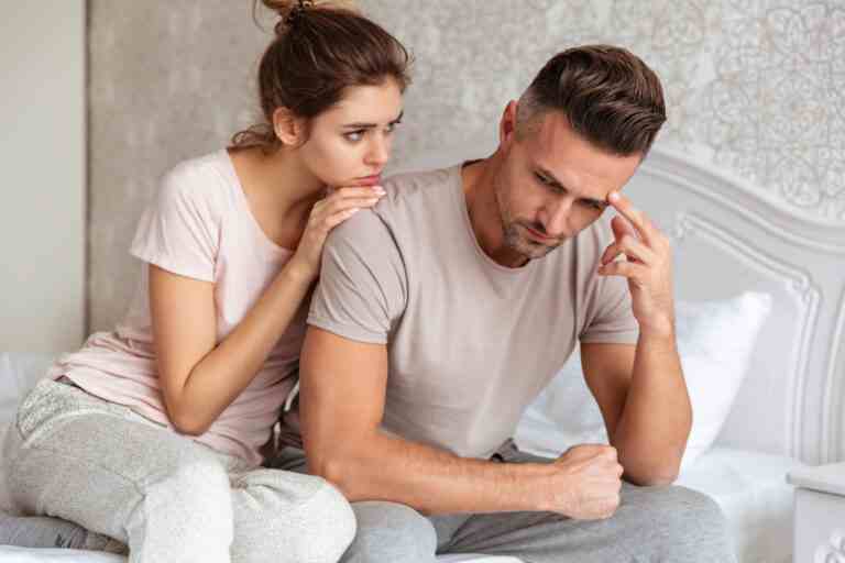 lovely couple sitting bed while woman calm down her boyfriend which upset