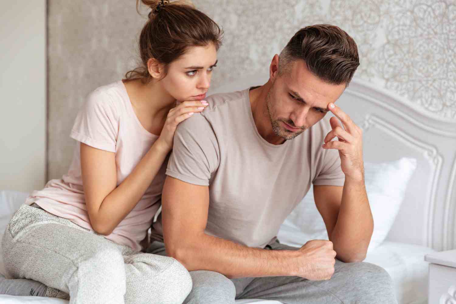 lovely couple sitting bed while woman calm down her boyfriend which upset