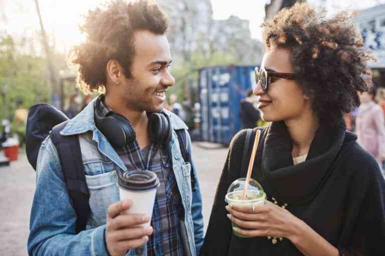 outdoor portrait two cute african american people hanging around park drinking coffee laughing talking