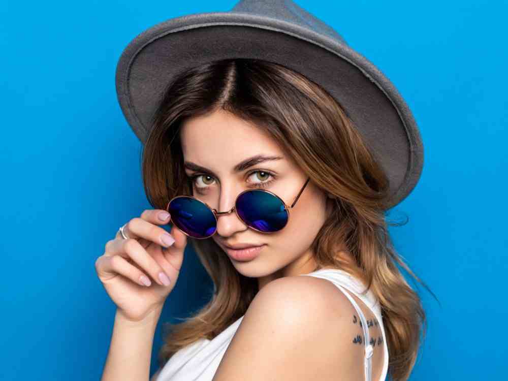 portrait pretty woman sunglasses hat blue colorful wall