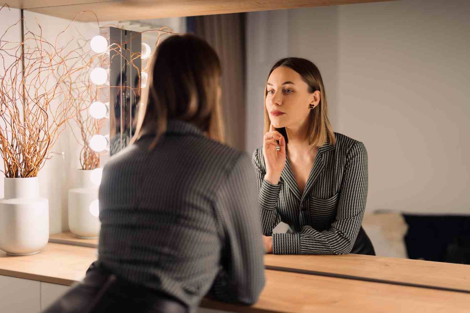 selfconfident woman looking her reflection into mirror indoors beautiful interior design