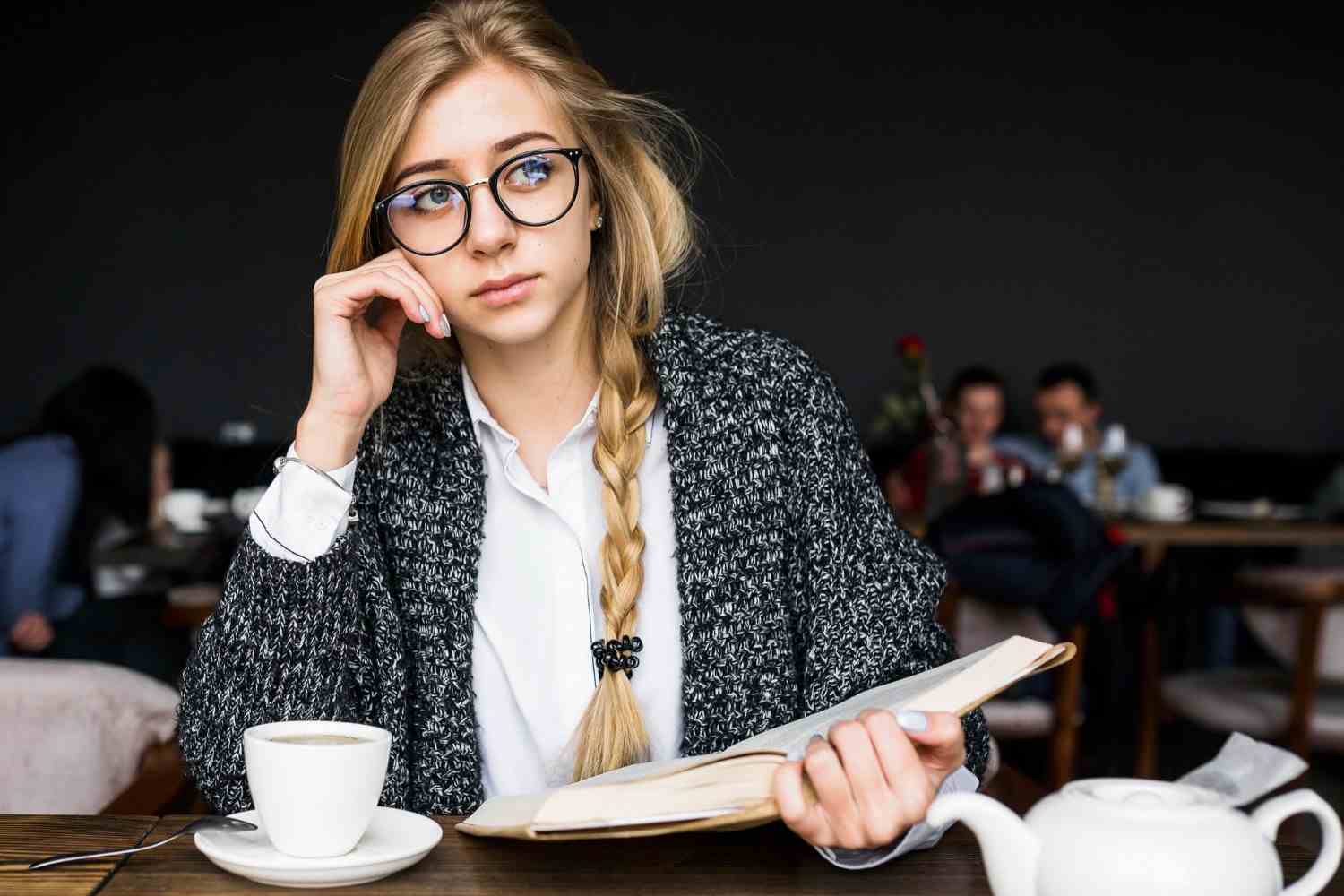 thoughtful woman with book cafe