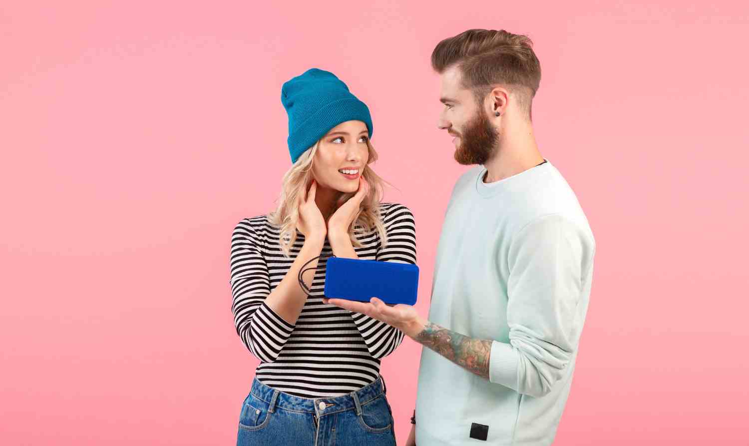 young couple listening music wireless speaker wearing cool stylish outfit smiling posing pink