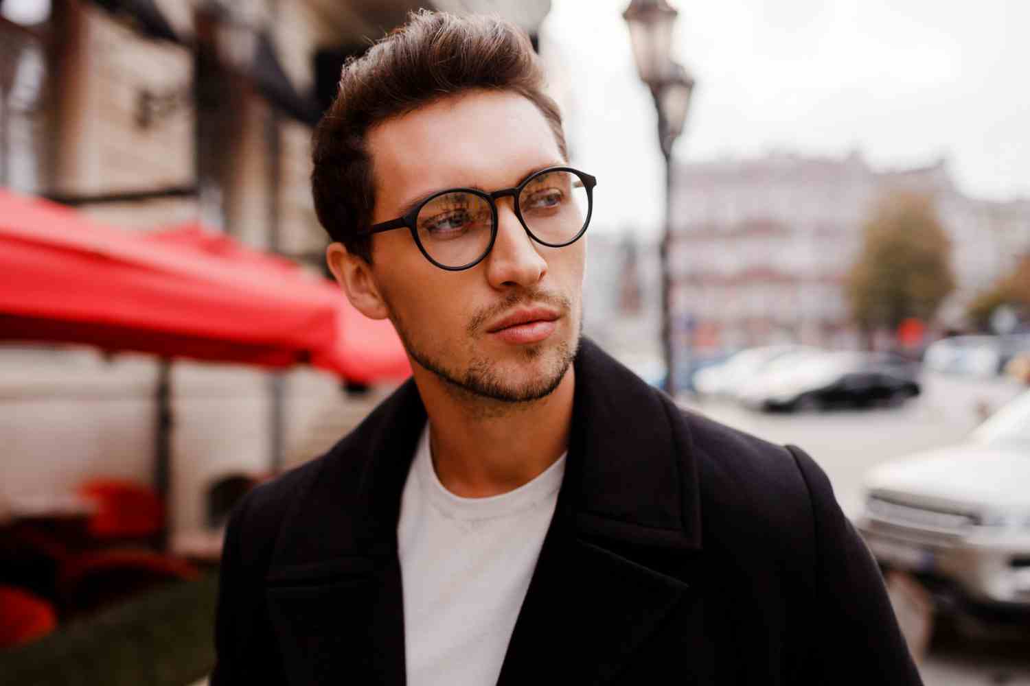 confident young man full suit looking away while standing outdoors european city wearing eyewear