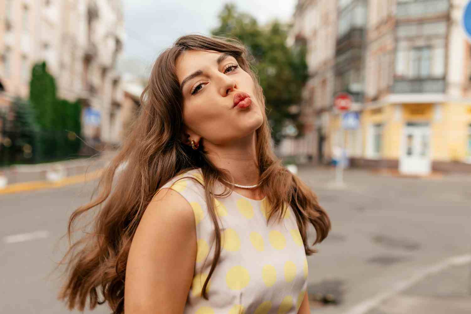 funny spectacular lovely girl with wavy flying hair from wind walking city sending kiss blurred city background european young girl posing tenderly