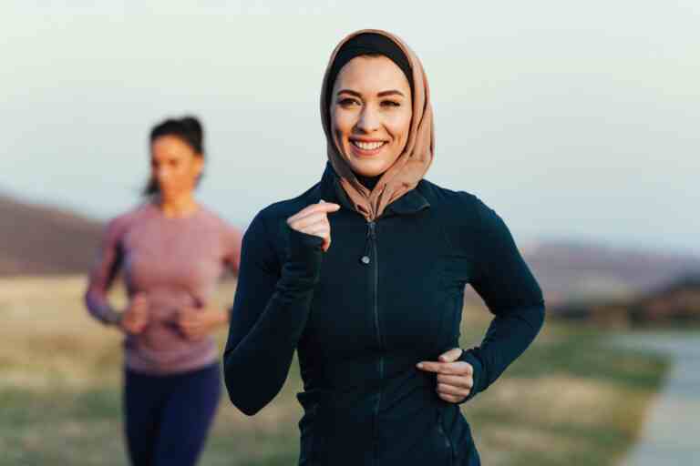 happy female athlete jogging morning nature her personal trainer is background