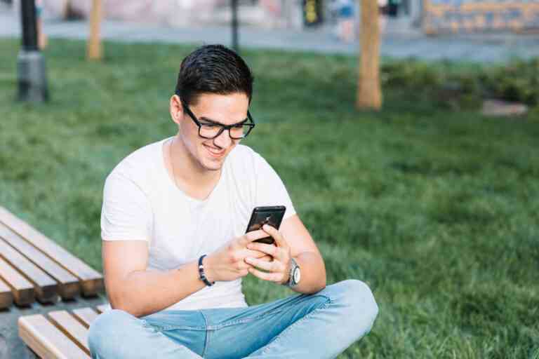 happy man sitting bench using cellphone