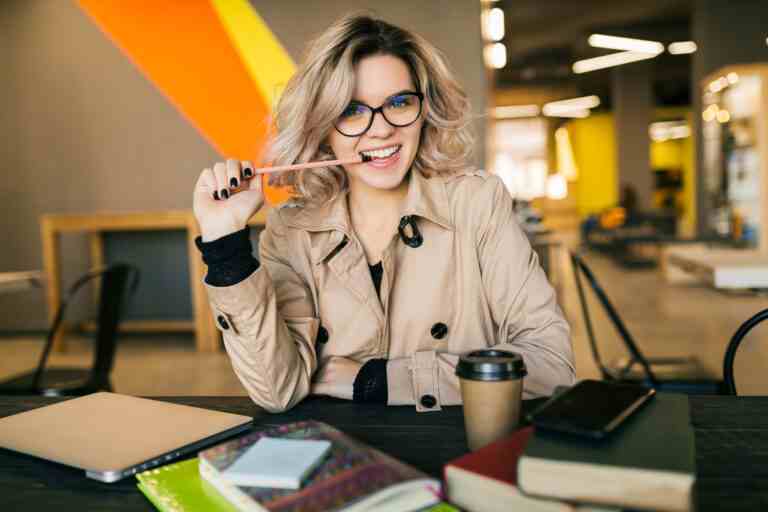 portrait young pretty woman having idea sitting table trench coat working laptop