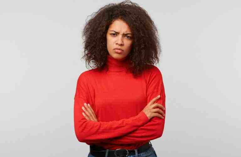 seriouswoman with curly afro hair standing with crossed hands frowning