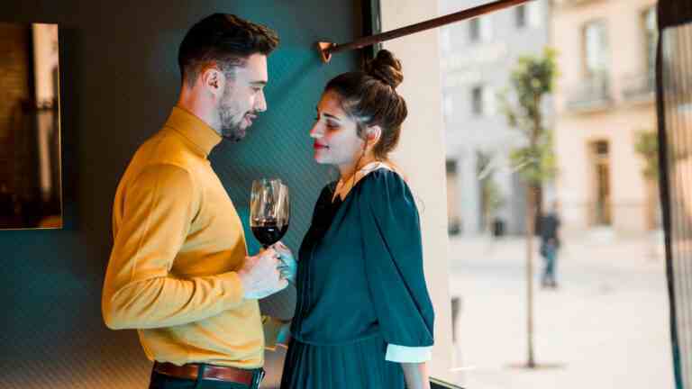 young man woman with glasses wine near window