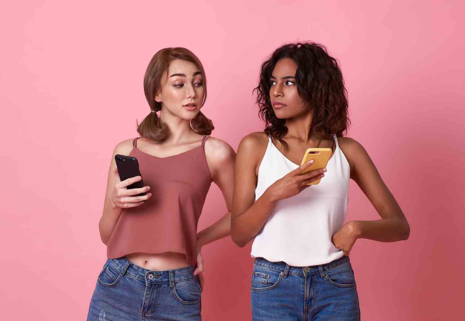young two women using mobile phone while brunette woman looks smartphone her friend