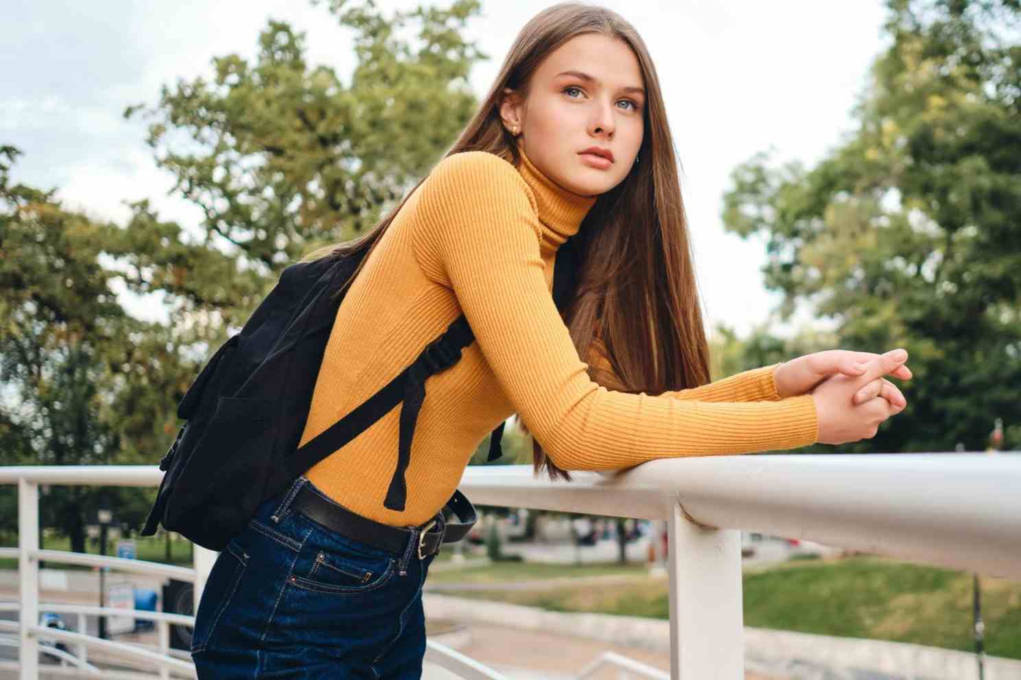 beautiful casual student girl with backpack intently looking away city park