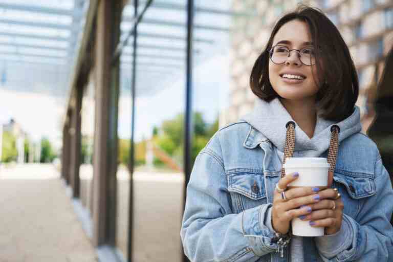 closeup portrait young happy pretty girl explore city look away with pleased cheerful face drinking coffee takeaway cup from favorite local cafe walking street fresh air enjoy spring