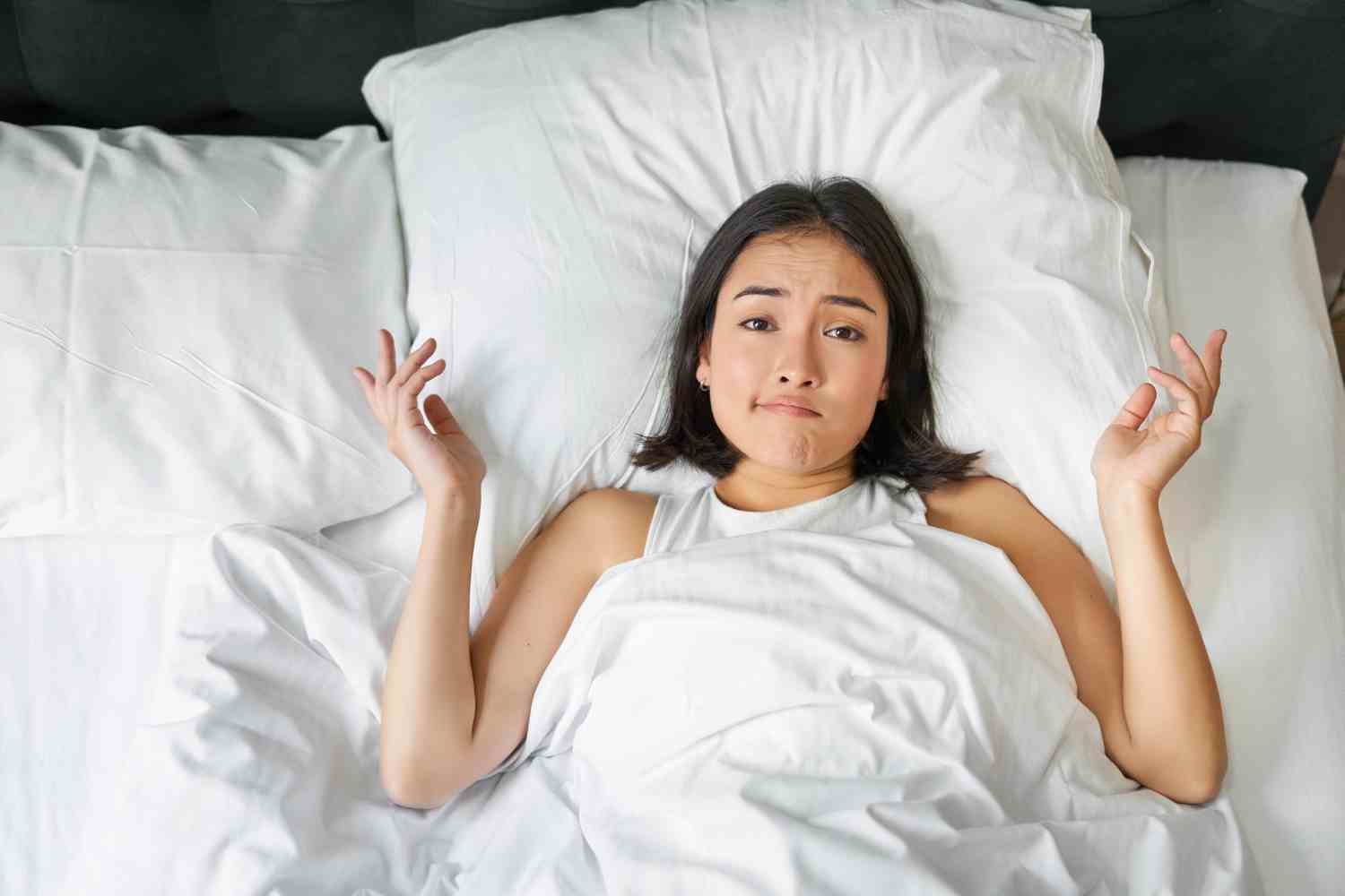portrait asian girl lying her bed shrugs looks puzzled overthinking before going sleep