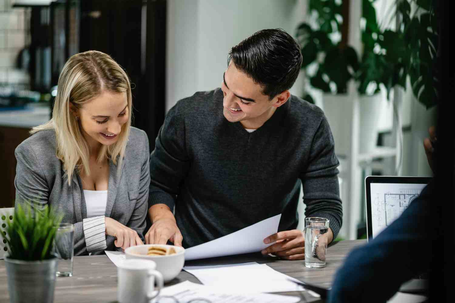 young happy couple going through their housing project blueprint during meeting with real estate agent